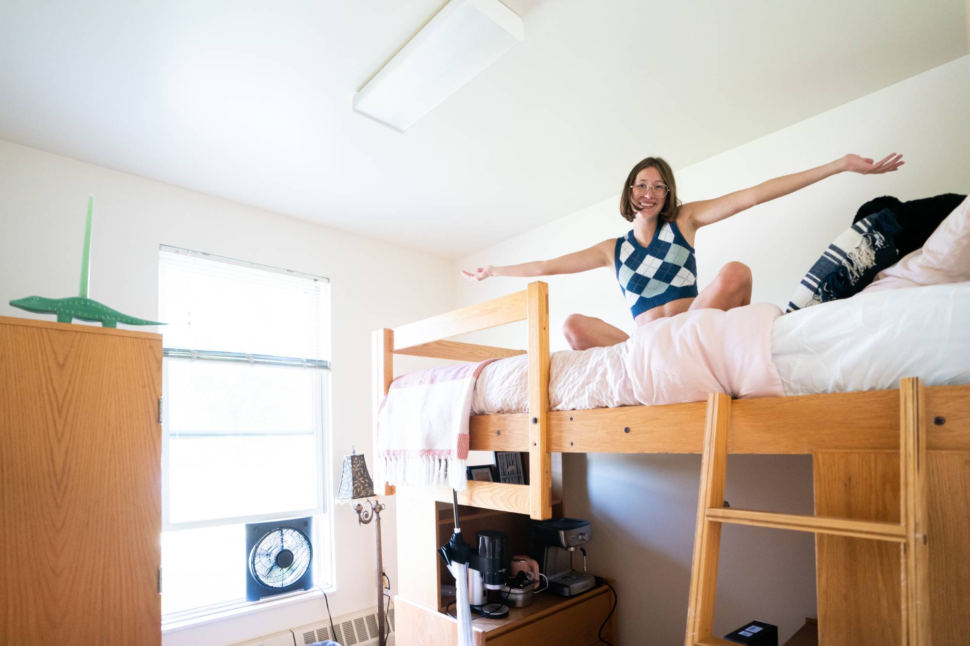 Student sitting in their loft bed in a living center during move-in